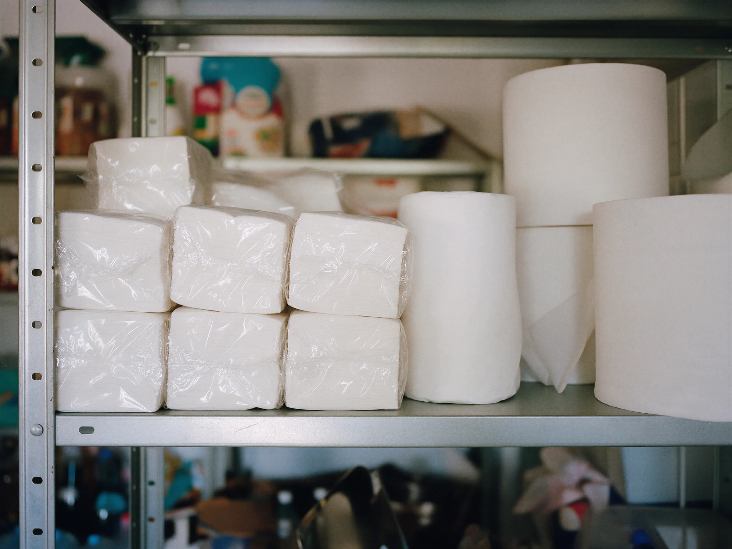 Paquetes de servilletas blancas y bobinas de papel industrial en una estantería